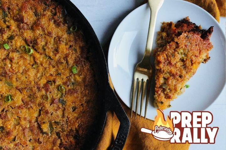 A pan full of Spicy Chorizo Dressing sits next to a small white plate with a serving of the dressing.