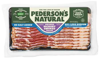 A package of Pederson's Natural Uncured Hickory Smoked Bacon, showing multiple slices of raw bacon arranged on a black tray inside a clear plastic vacuum bag. The packaging features a label with green, white, and blue sections.